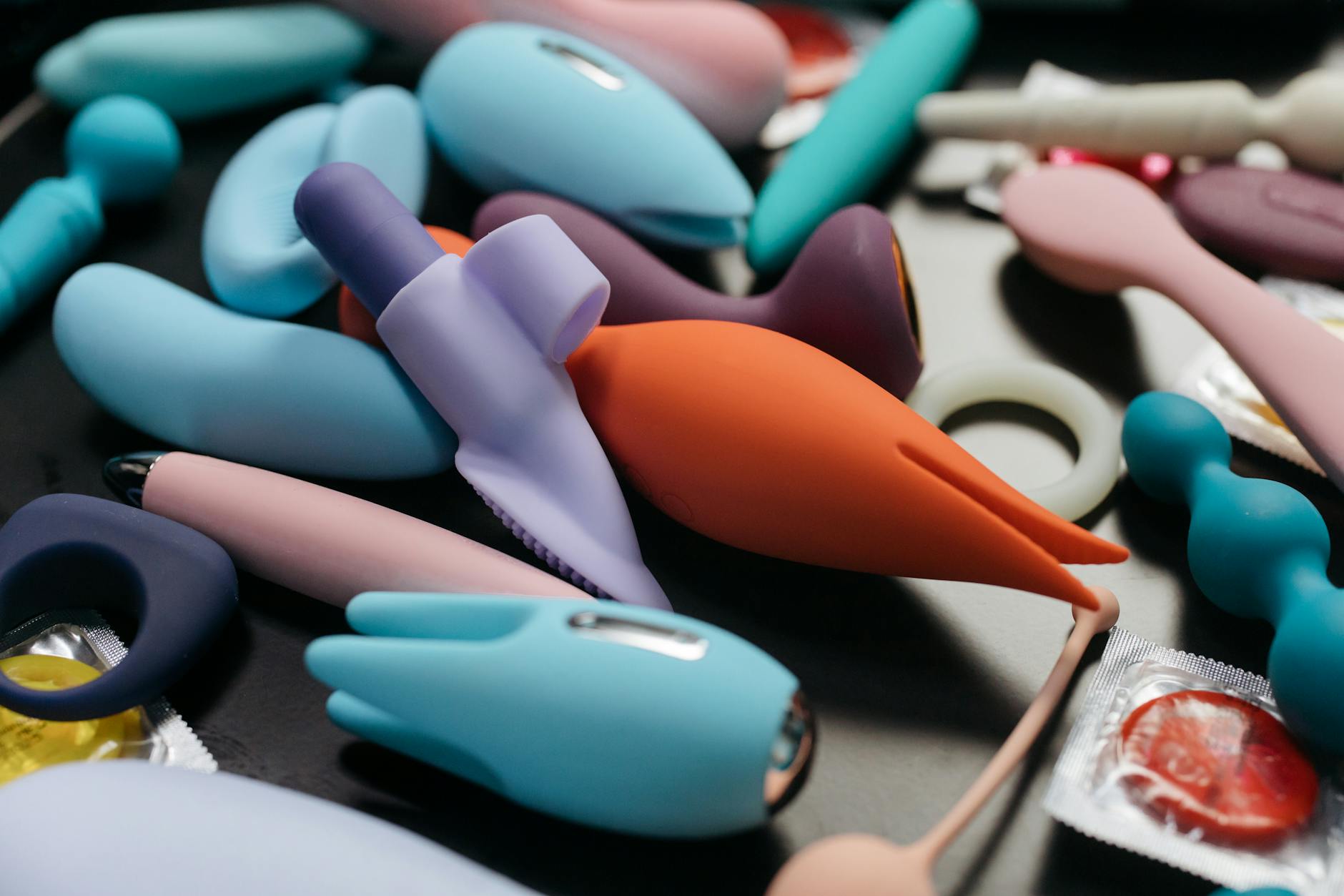 Woman holding a pink clitoral vibrator with books nearby