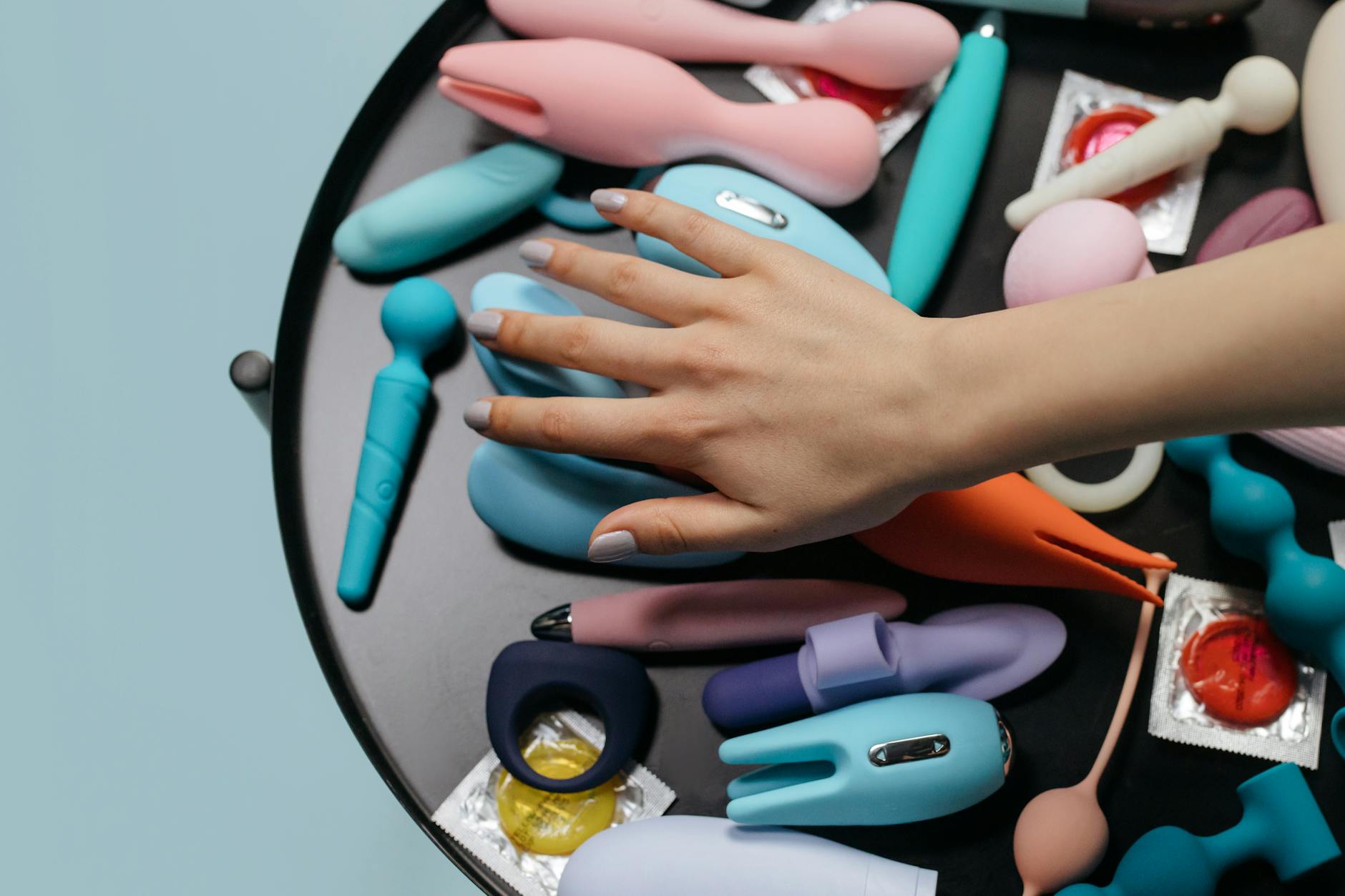 A hand holding a vibrator against a purple backdrop, representing modern pleasure and personal agency.