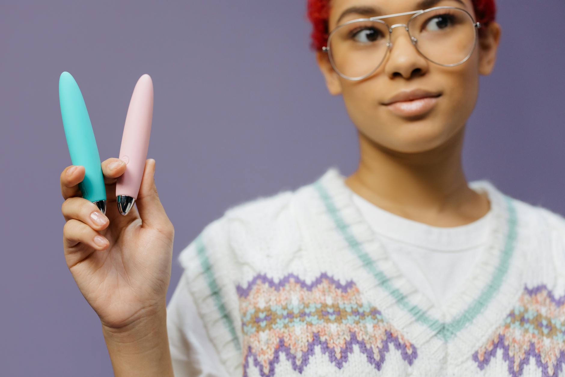 A person holding two colorful vibrators, exploring different techniques for pleasure.