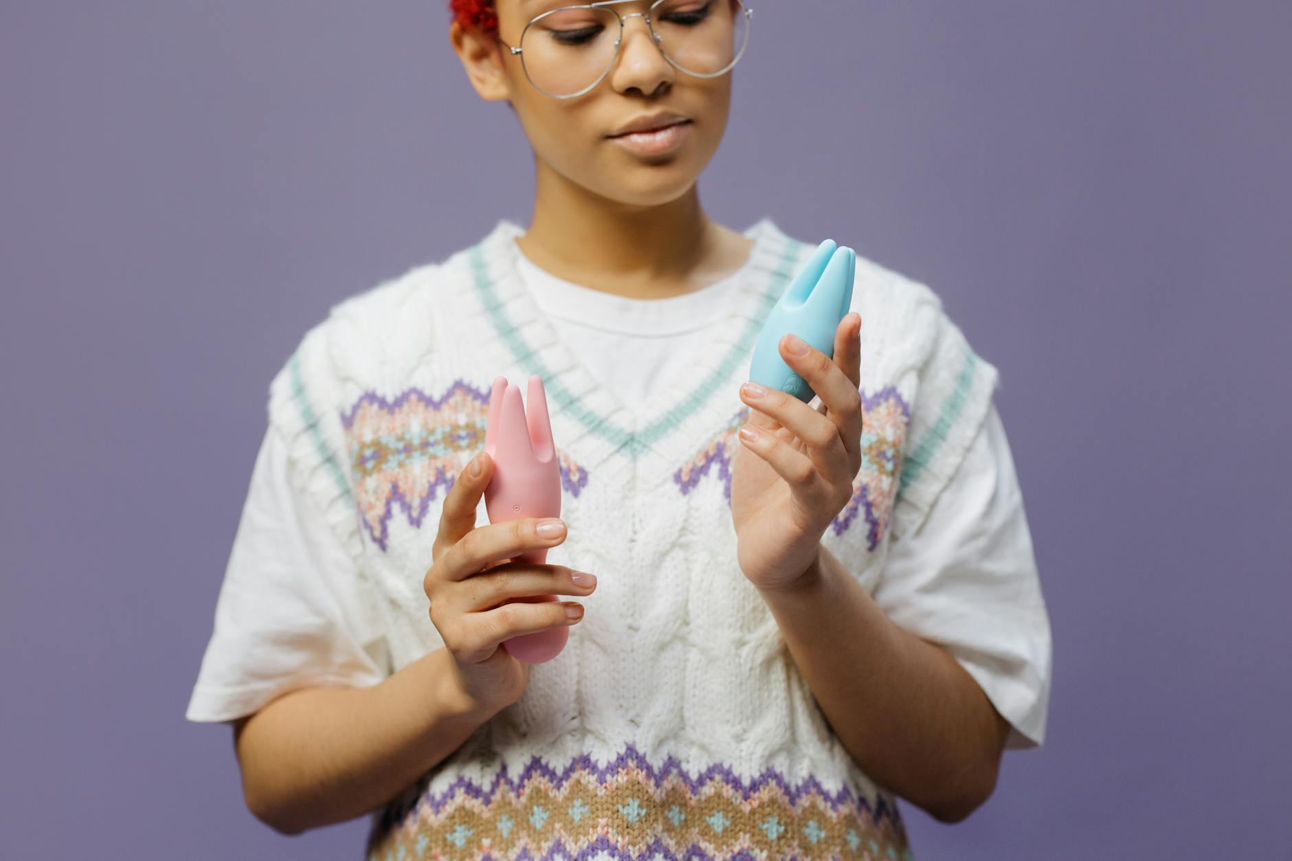 Woman thoughtfully holding a blue silicone vibrator, representing pleasure and self-knowledge in later adulthood.